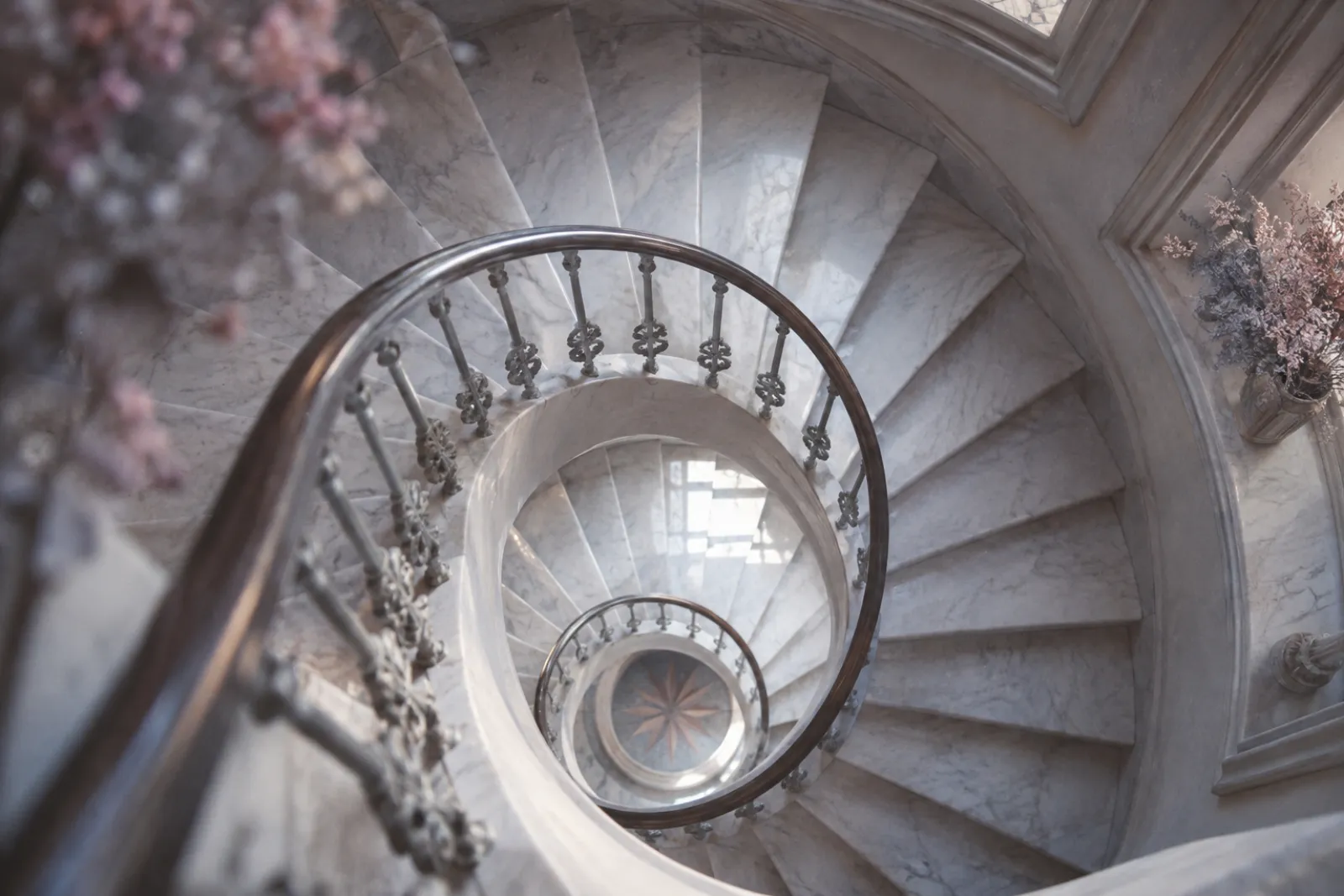 Looking down a stairwell from above, a pale marble spiral