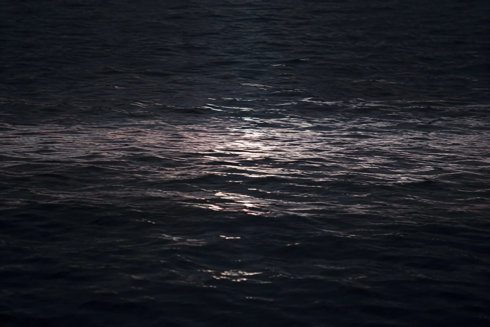 Dark still water at night with a band of moonlight across it