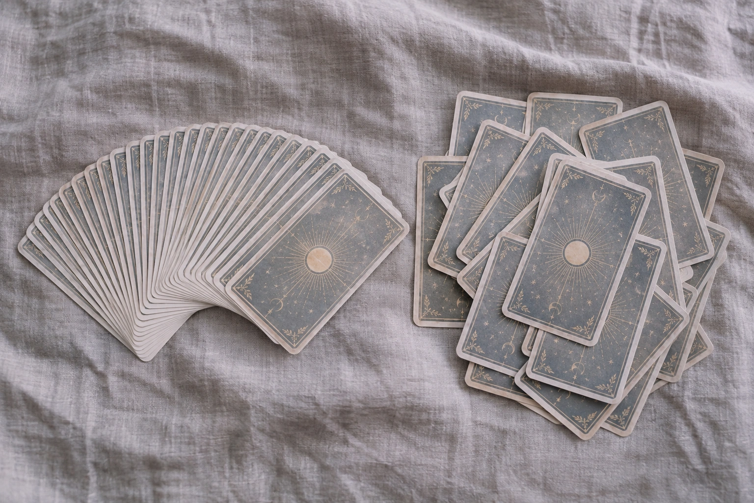 Two decks side by side on linen seen from above, the left one in an even fan, the right one in a loose overlapping pile